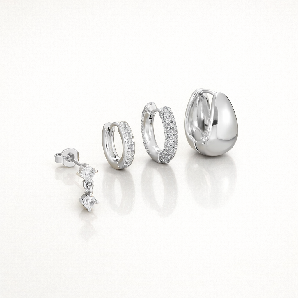 Roxy Set in silver tone, a dangling crystal drop stud, a plain hoop, a pave hoop, and a chunky teardrop hoop.