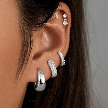 Roxy Set in silver tone worn on the ear, a cartilage drop stud above a stack of pave and teardrop hoops.