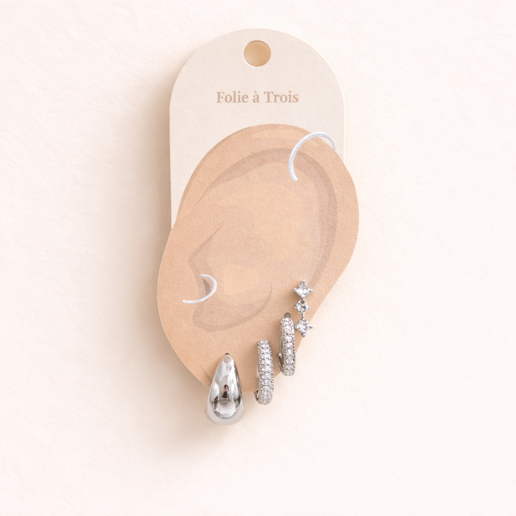 Illustrated Folie a Trois earring card showing the silver-tone Roxy Set pieces on an ear-shaped display.