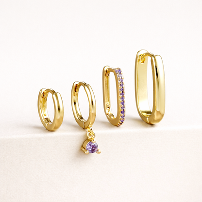 The Sabrina SET is shown in a purple crystal colorway, with pave and dangling stones on two of the four gold hoops.