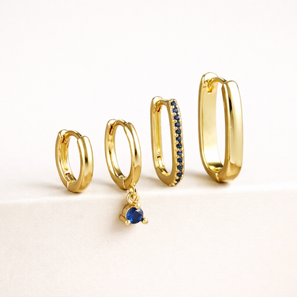 The Sabrina SET is shown in a blue crystal colorway, with pave and dangling stones on two of the four gold hoops.