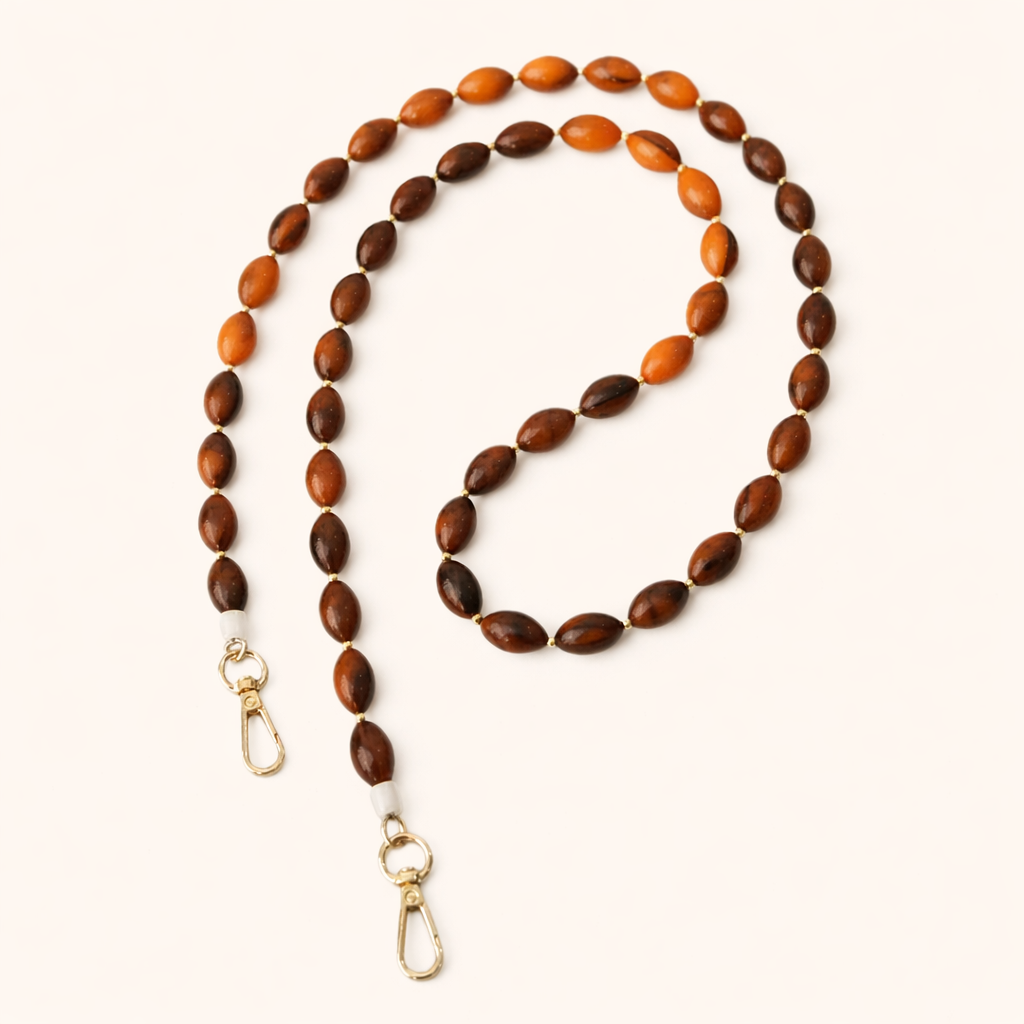 Saffron Long Phone Strap coiled flat, showing the amber and brown oval beads with gold clasp ends.