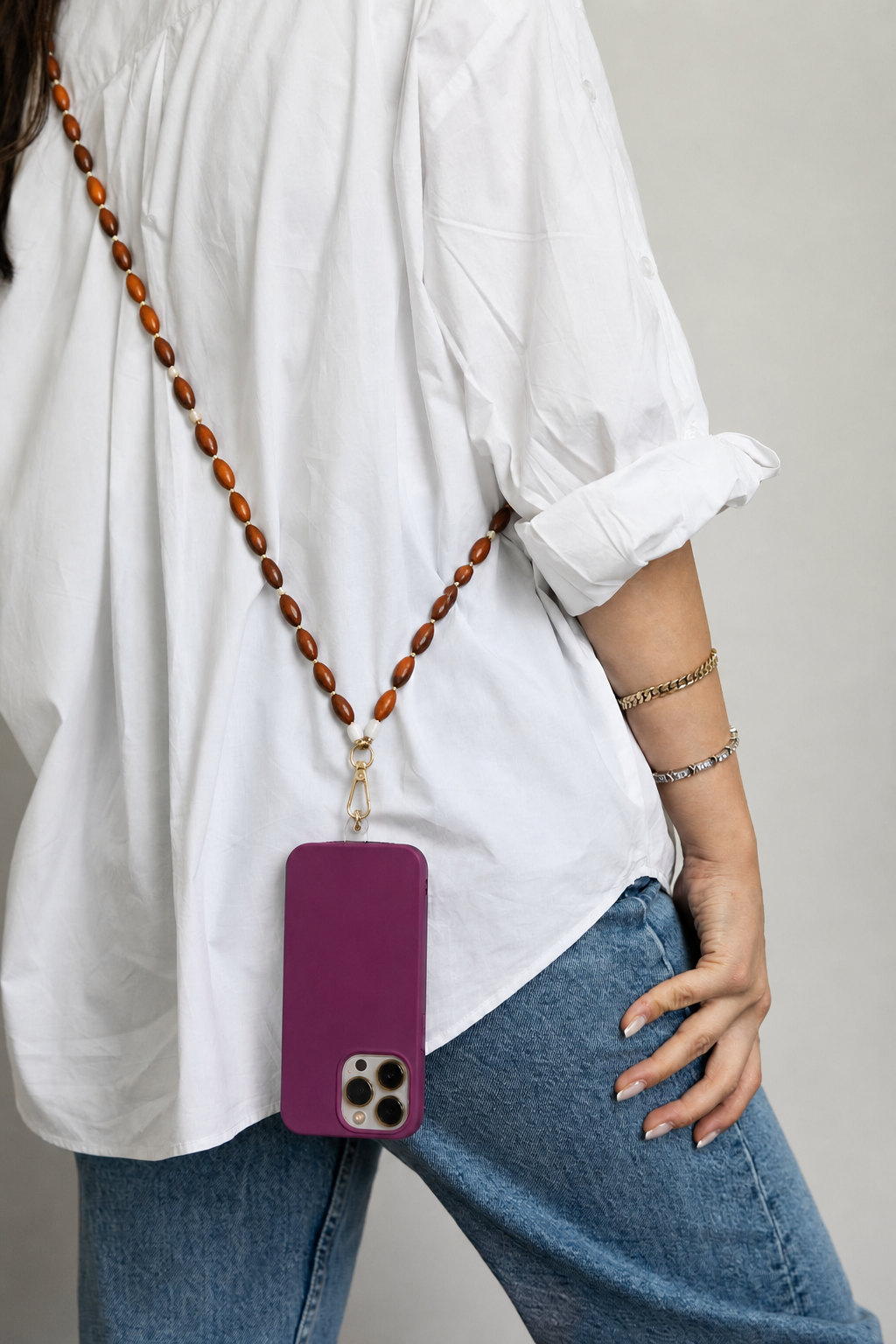 Saffron Long Phone Strap worn crossbody, its amber and brown beads paired with a purple phone case.