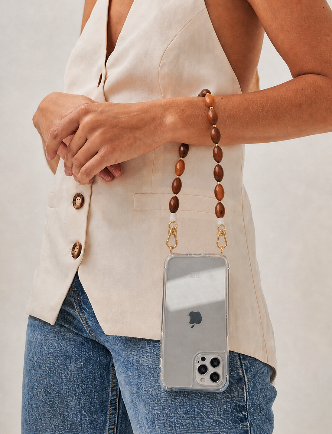 Model wears the wood-bead Saffron strap on her wrist, holding a phone in a clear case.