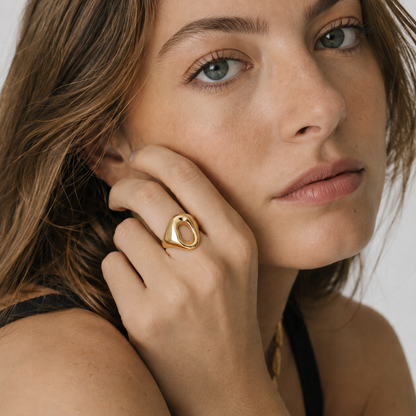 Model wears the gold Salt Air RING with its asymmetric open oval face, hand raised to her cheek.