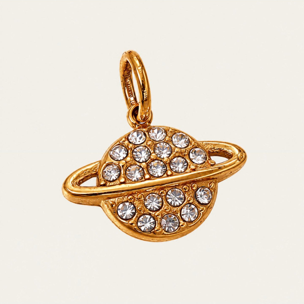 The Saturn CHARM in gold, a ringed planet pendant set with clear rhinestones, shown in close-up product photography.
