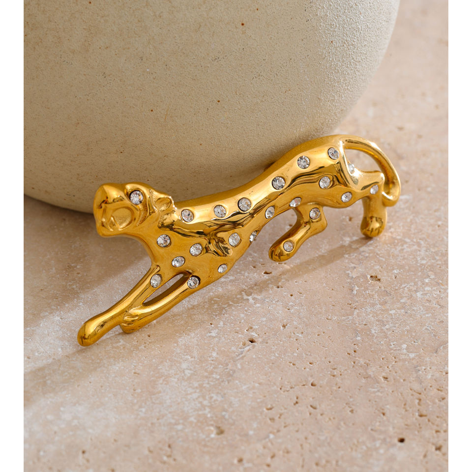 Gold leopard-shaped crystal brooch styled beside a ceramic vase on a stone surface — Folie à Trois Savana BROOCH