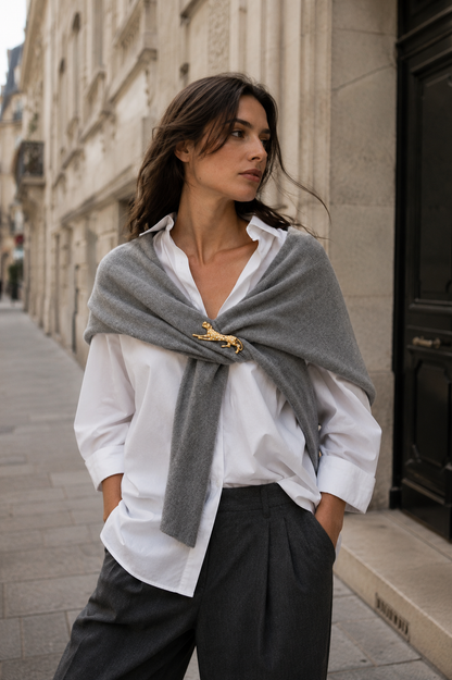 Model wears a gold leopard Savana BROOCH pinned to a grey wrap over a white shirt on a city street — Folie à Trois