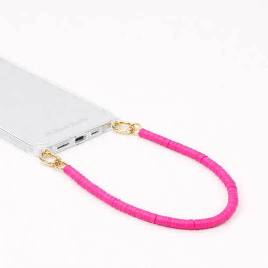 Hot pink heishi bead Scottie SHORT PHONE CORD clipped to a clear phone case with gold hardware.
