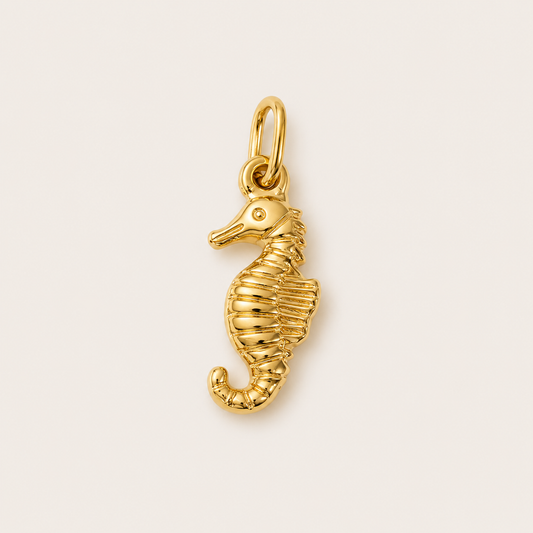 The Seahorse CHARM in gold, a detailed seahorse pendant with a ridged textured body, shown in close-up studio photography.