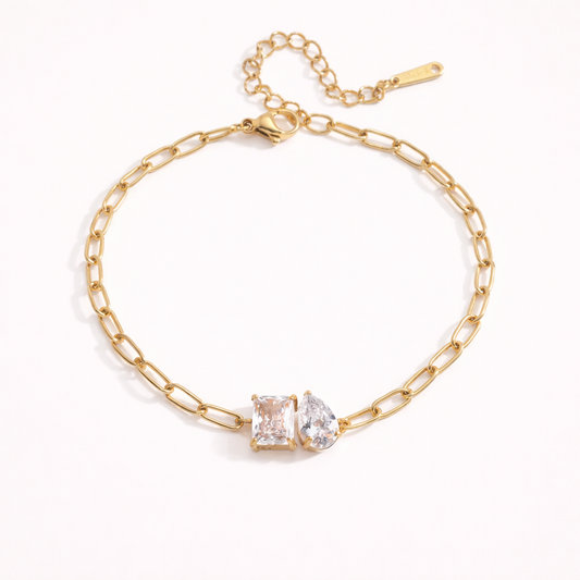 Sharp Halo BRACELET gold paperclip chain with a clustered rectangular and teardrop crystal centerpiece, studio flat-lay on beige.