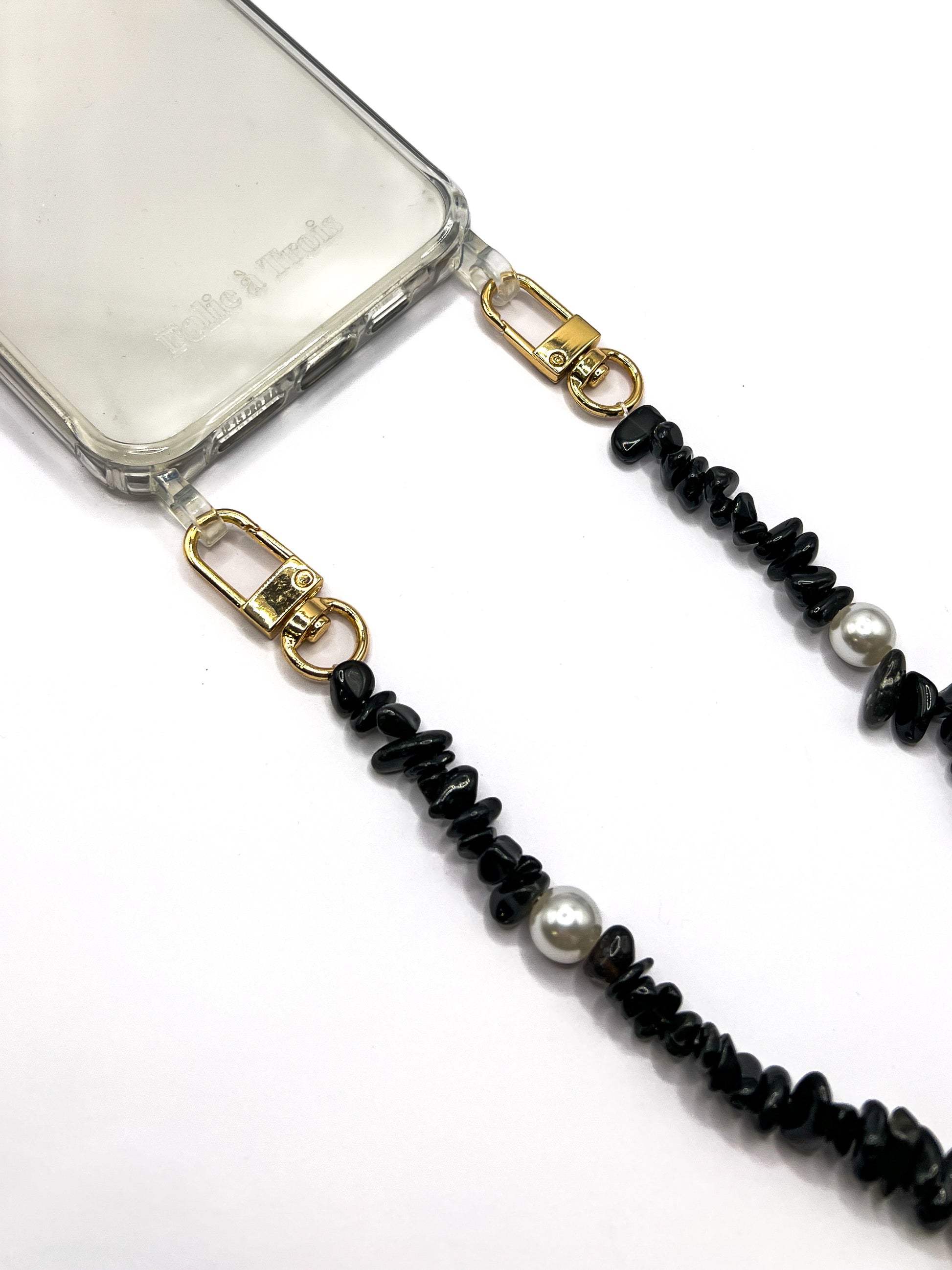 Close-up of a black beaded Shell Whisper SHORT PHONE STRAP with gold-tone clasps, attached to a clear phone case.