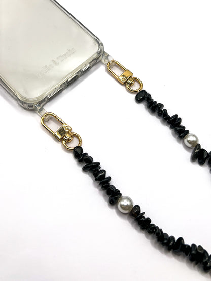 Close-up of a black beaded Shell Whisper SHORT PHONE STRAP with gold-tone clasps, attached to a clear phone case.