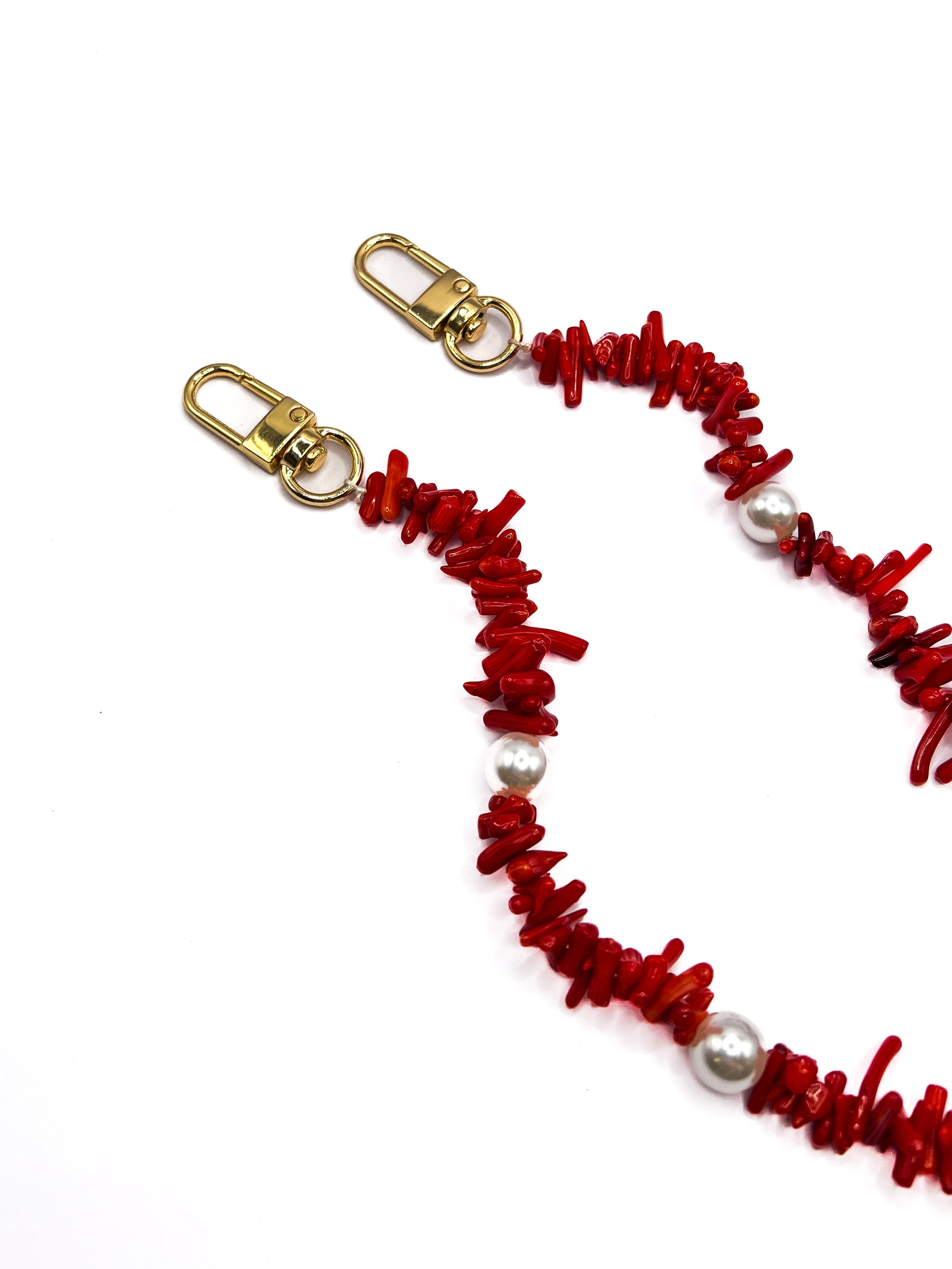 Close-up of a red beaded Shell Whisper SHORT PHONE STRAP with gold-tone clasps, no phone attached.