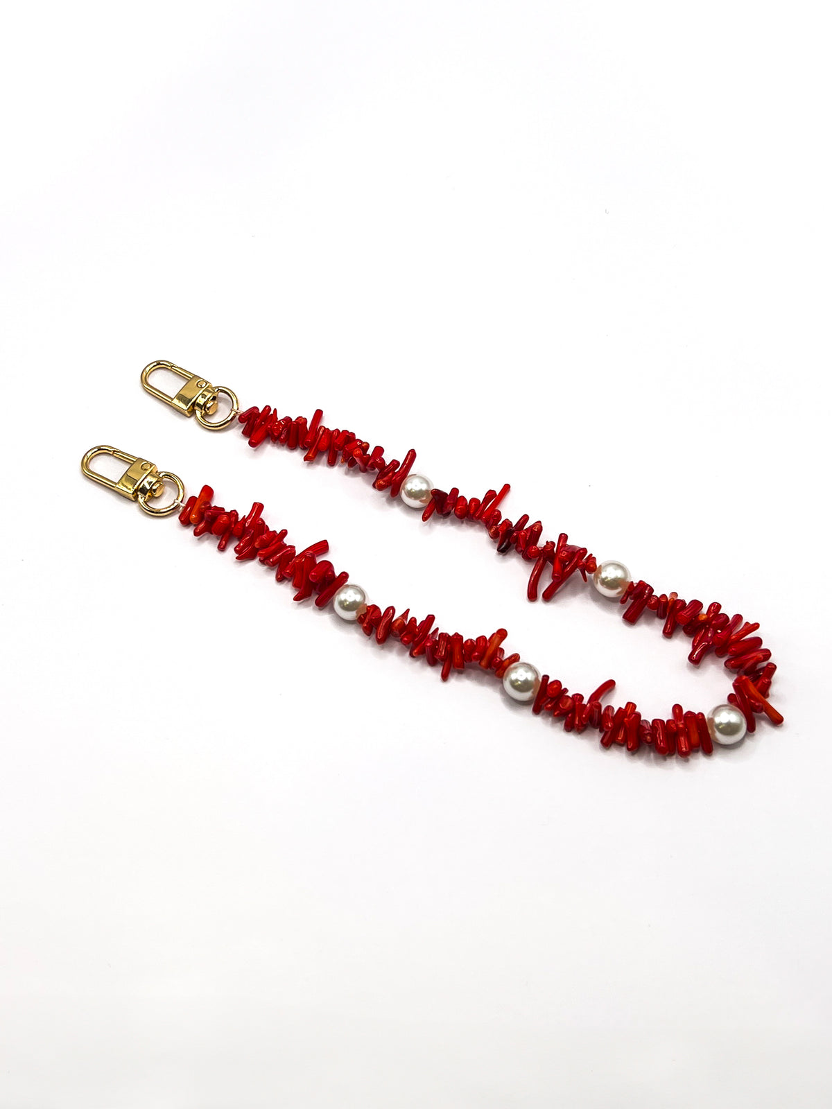 Red beaded Shell Whisper SHORT PHONE STRAP laid flat with gold-tone clasps on a white background.