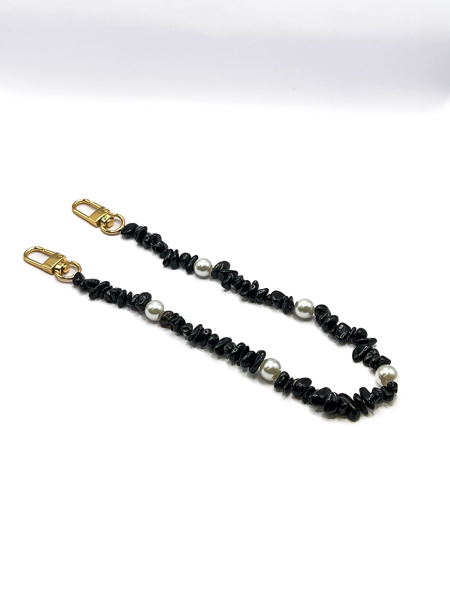 Black beaded Shell Whisper SHORT PHONE STRAP laid flat with gold-tone clasps on a white background.