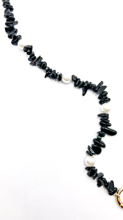 Close-up of a black beaded Shell Whisper SHORT PHONE STRAP, chip beads and pearls, gold clasp visible at the edge.