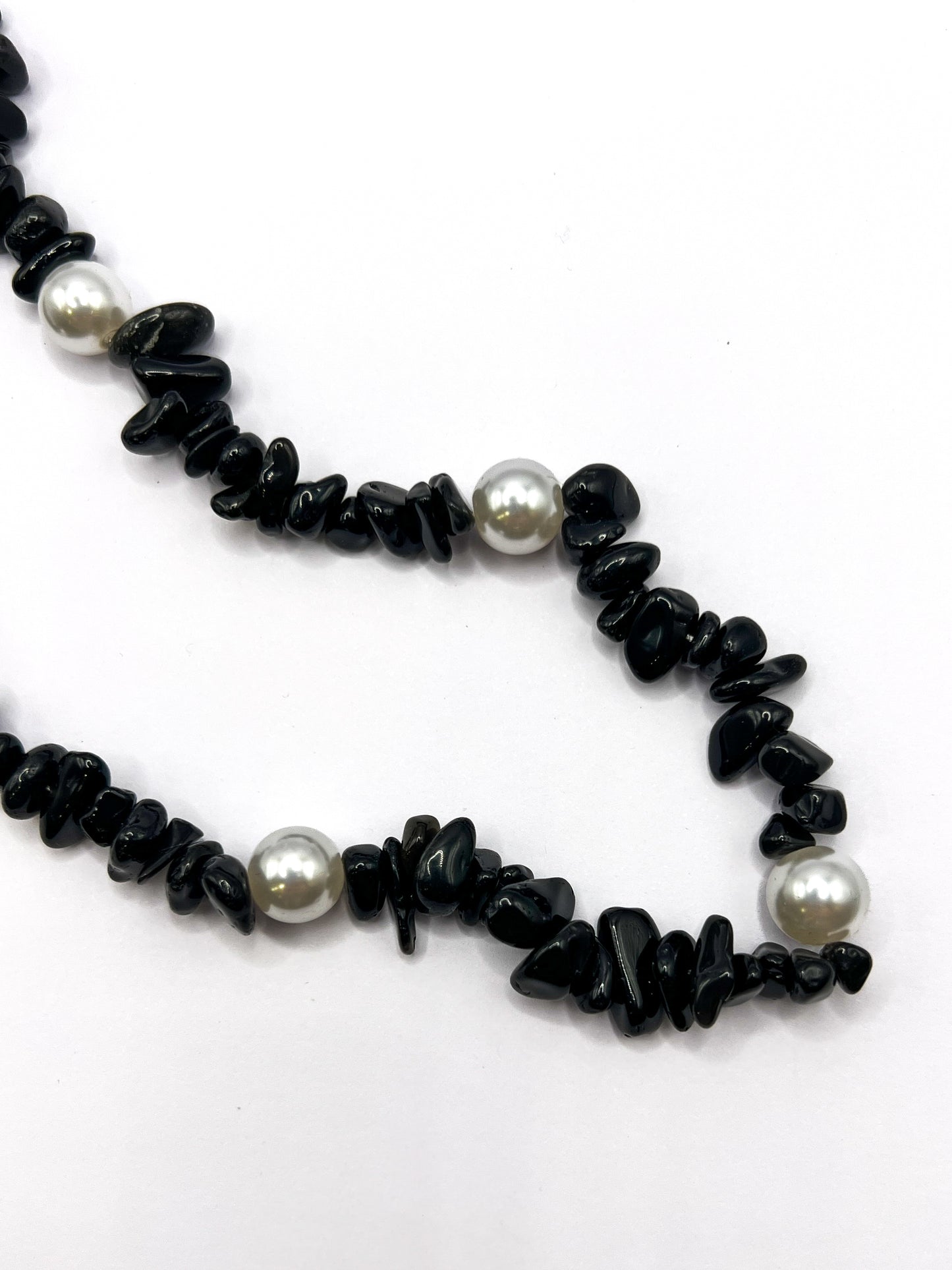 Close-up detail of a black beaded Shell Whisper SHORT PHONE STRAP, showing the chip beads and pearl accents.