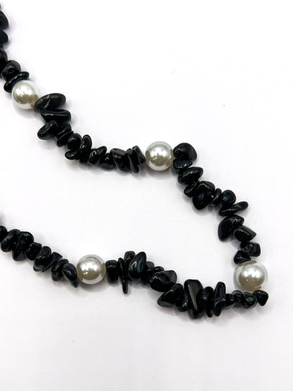 Close-up detail of a black beaded Shell Whisper SHORT PHONE STRAP, showing the chip beads and pearl accents.