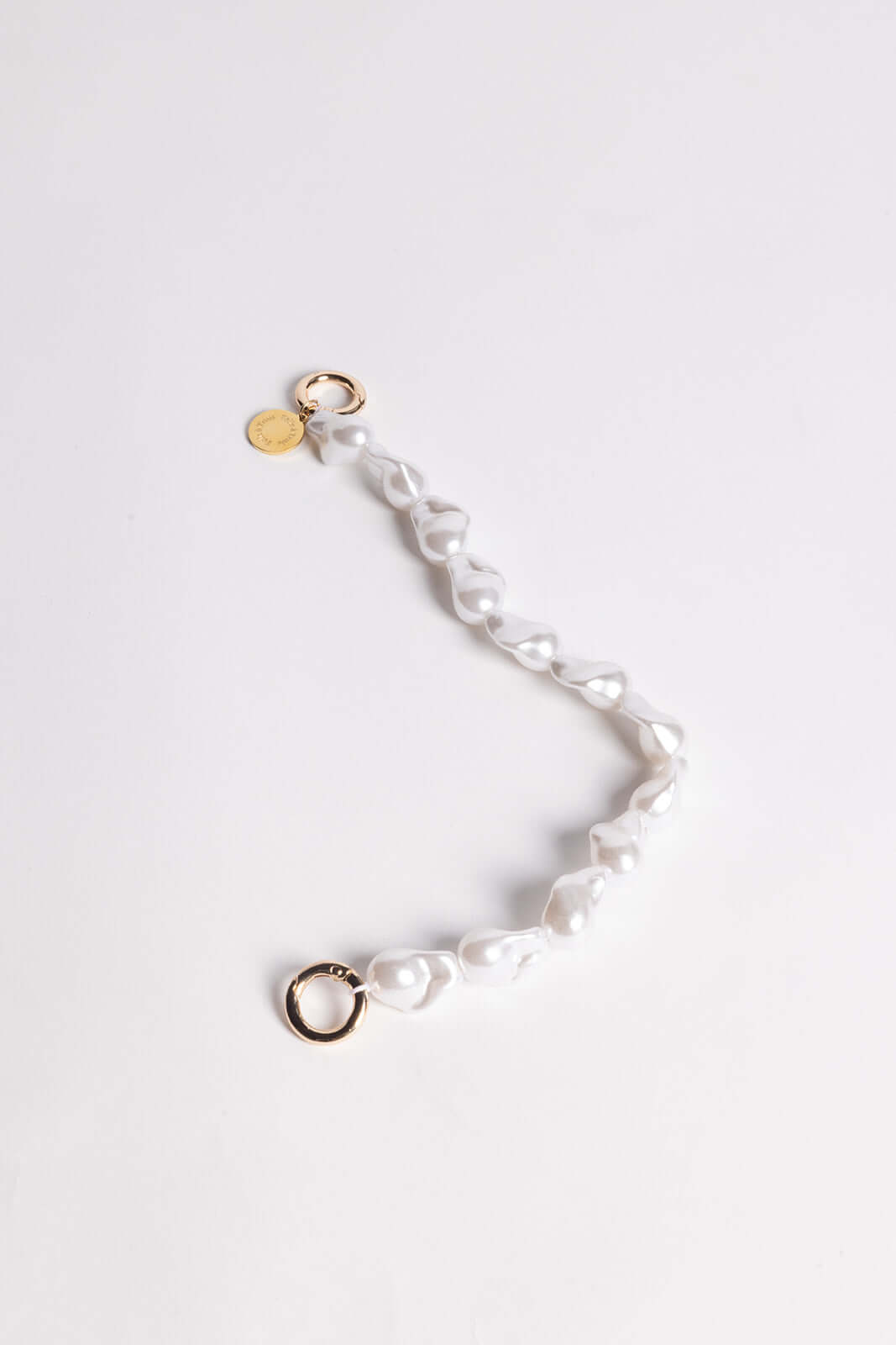 Baroque pearl Short Pearl PHONE STRAP shown alone in a curved shape with gold-tone clasps on a white background.