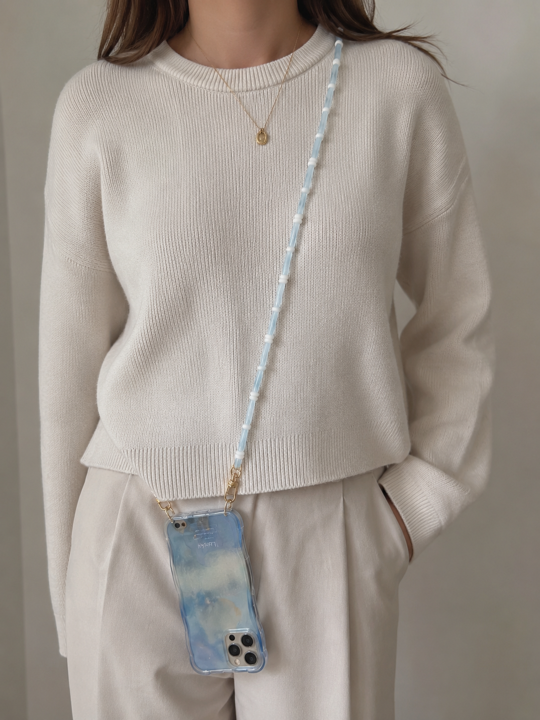 Woman wearing a light blue Smooth Moves PHONE CHAIN with a blue tie-dye phone case over a cream sweater.