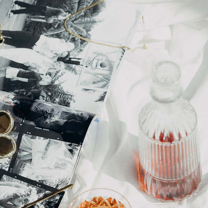 The Snake Skin NECKLACE in gold, glimpsed beside vintage photo prints, a perfume bottle, and jewelry in a styled flat lay.