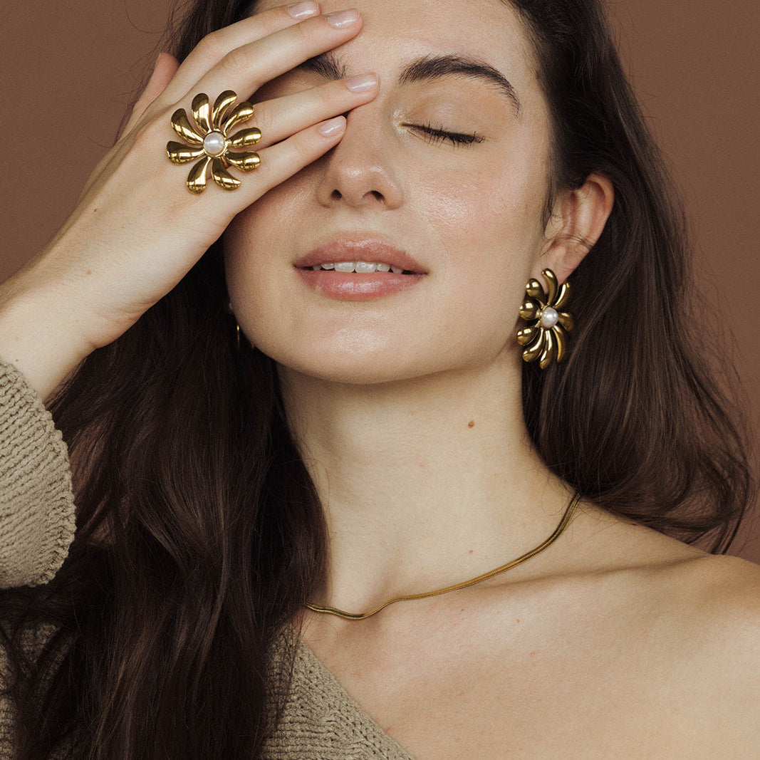 The Snake Skin NECKLACE in gold worn as a choker at the neckline, styled with matching floral gold ring and earrings.