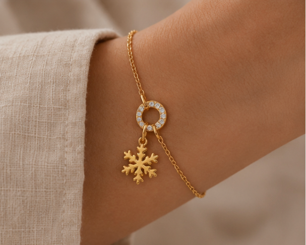 The Snowflake CHARM worn on a gold bracelet with a pave circle connector, dangling delicately at the wrist.