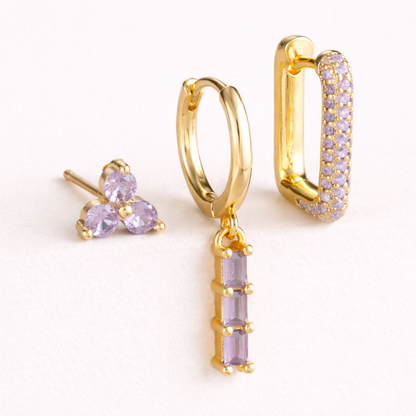 The Solaire SET is shown in a purple crystal colorway across its trio stud, drop huggie, and pave hoop.