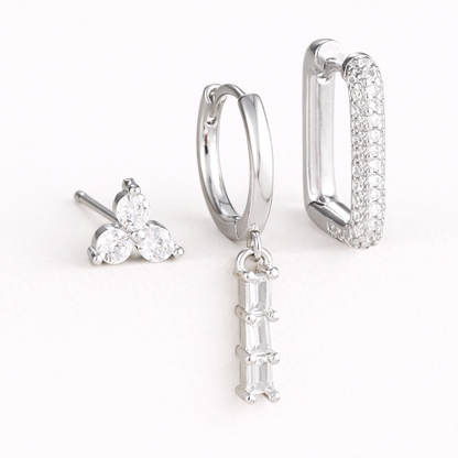 The Solaire SET is shown in clear crystals across its trio stud, drop huggie, and pave rectangle hoop.