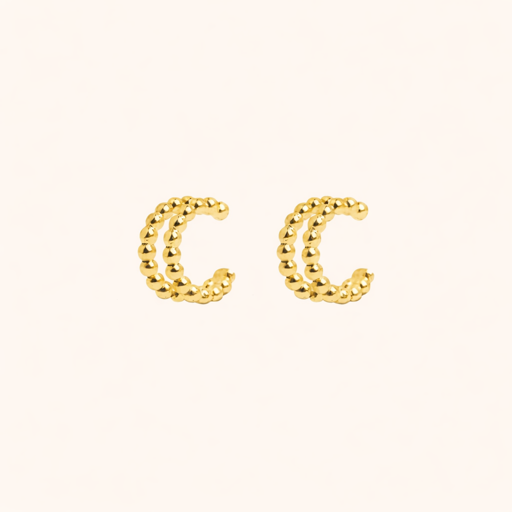 The Solara EARCUFF in gold, a pair of double-band beaded cuffs shown side by side on a cream background.
