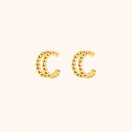 The Solara EARCUFF in gold, a pair of double-band beaded cuffs shown side by side on a cream background.