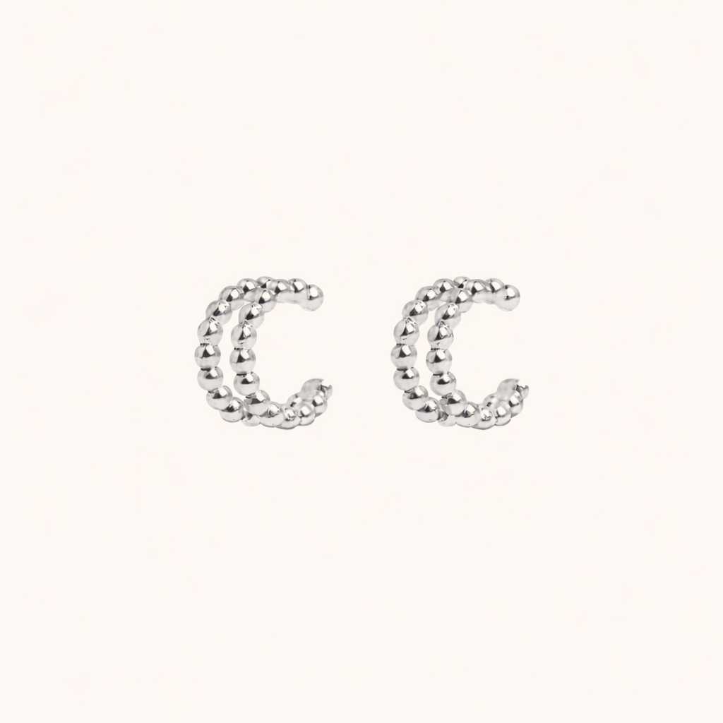 The Solara EARCUFF in silver, a pair of double-band beaded cuffs shown side by side on a cream background.