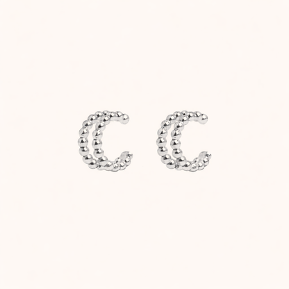 The Solara EARCUFF in silver, a pair of double-band beaded cuffs shown side by side on a cream background.