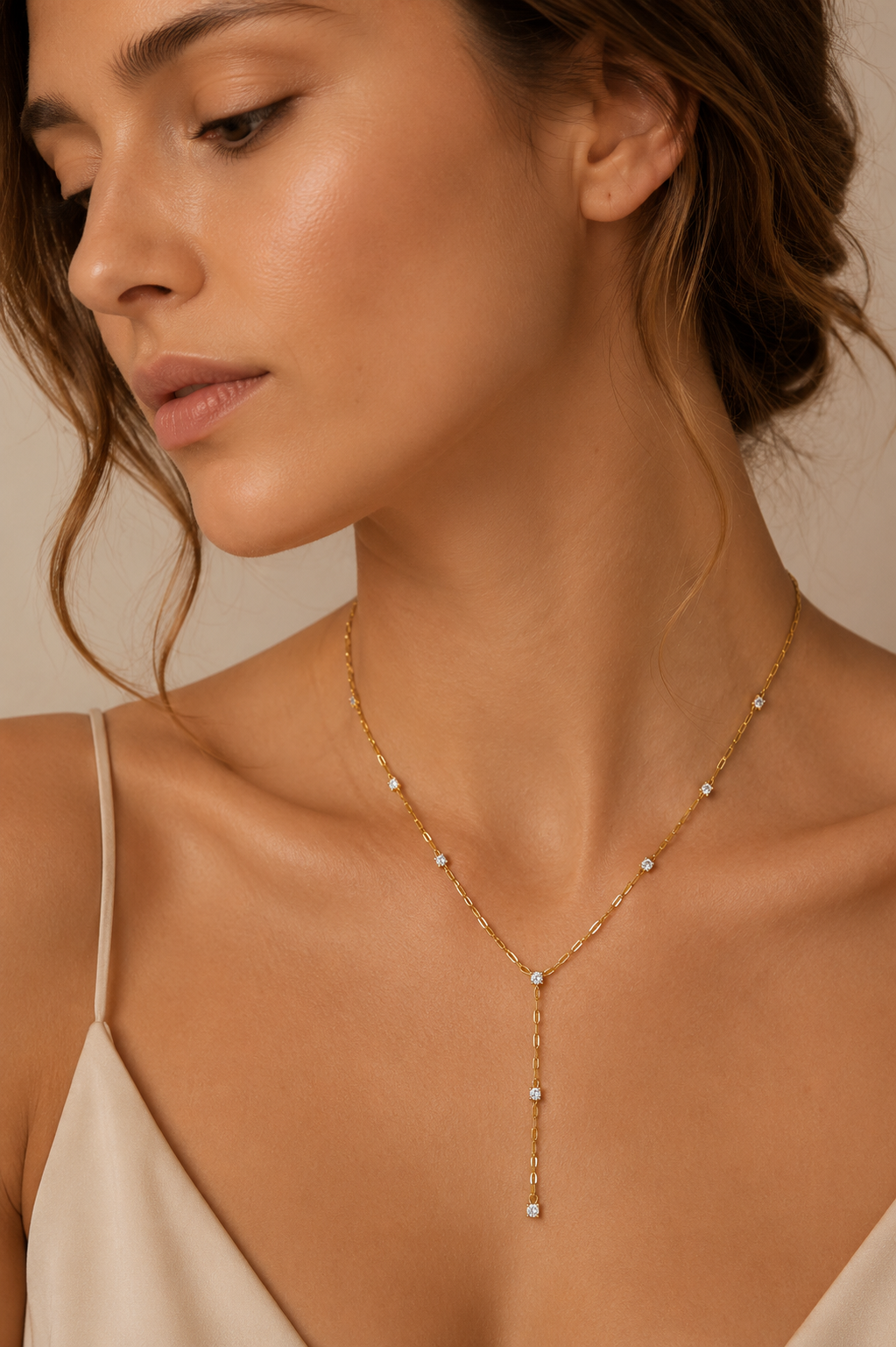 Model wears the gold Soleil Y NECKLACE with its paperclip chain and crystal drop resting at the neckline.