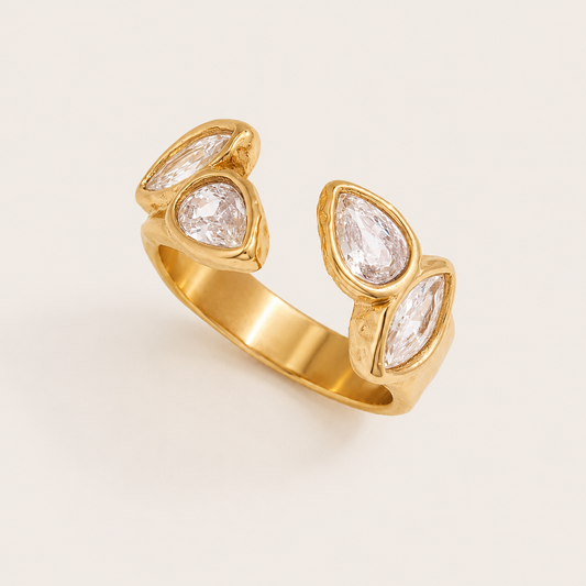 Gold open ring set with four bezel pear and marquise zirconia stones along the band, on a cream backdrop — Folie à Trois Solene RING.