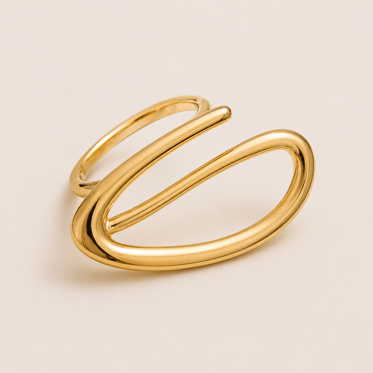 Gold open ring with a looping wire spiral forming an elongated oval, shown in close-up on a cream backdrop — Folie à Trois Solstice RING.