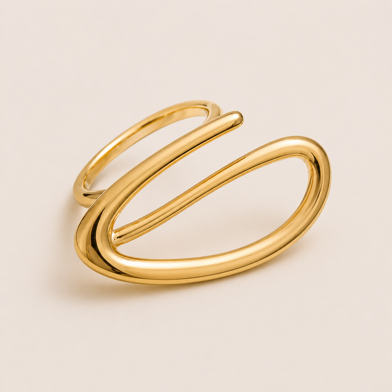 Gold open ring with a looping wire spiral forming an elongated oval, shown in close-up on a cream backdrop — Folie à Trois Solstice RING.