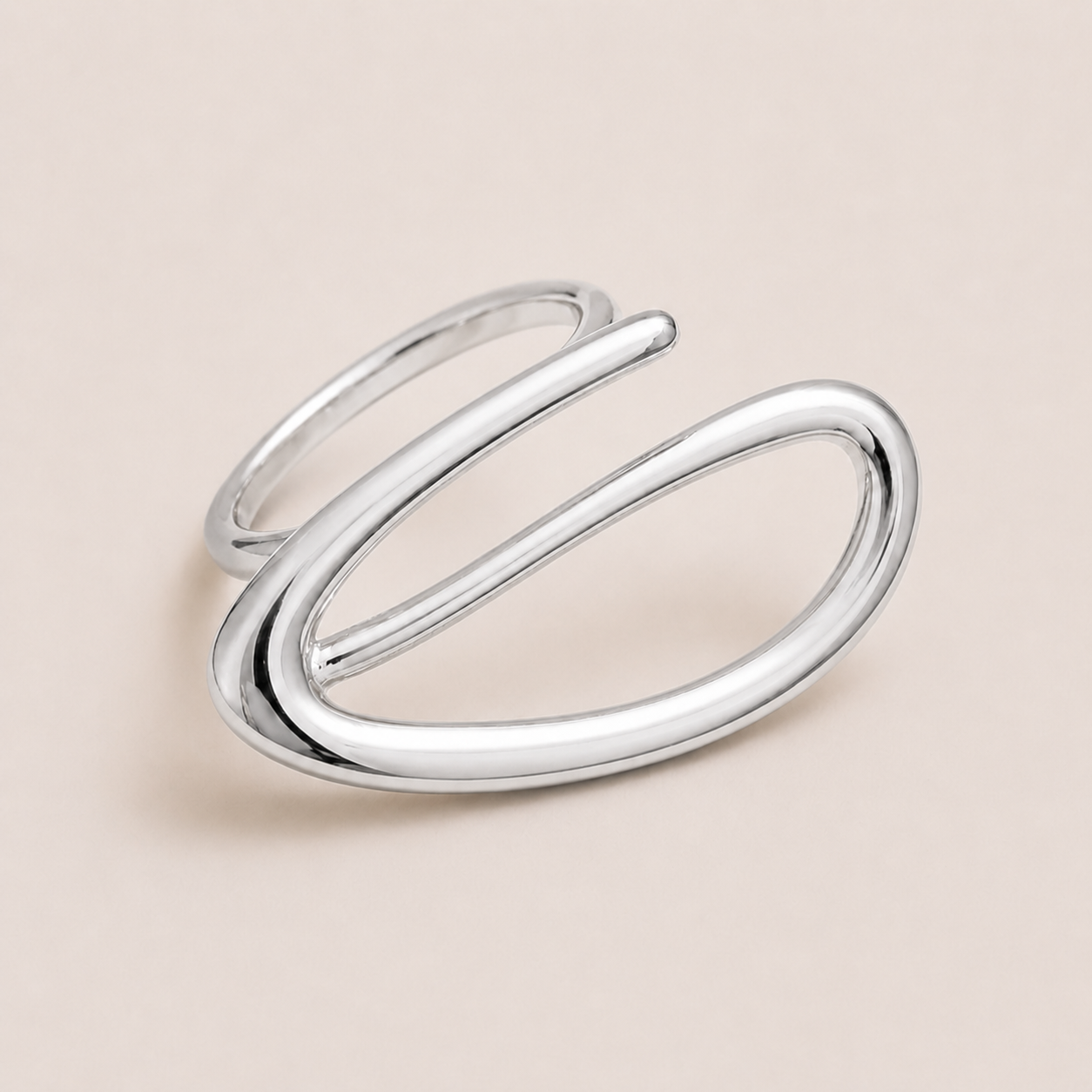 Silver open ring with a looping wire spiral forming an elongated oval, shown in close-up on a cream backdrop — Folie à Trois Solstice RING.