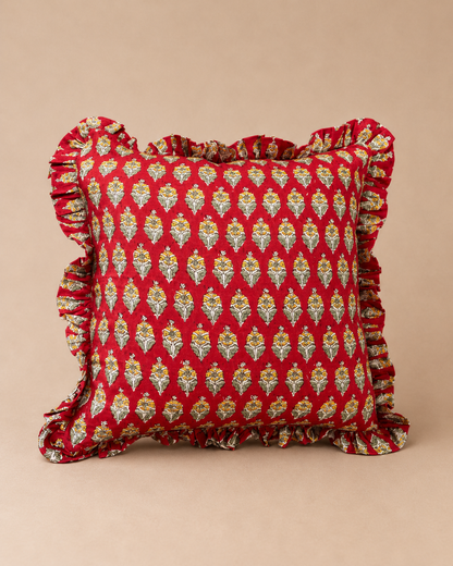 Red square cushion with a repeating cream and yellow floral bud print and ruffled trim, the Sonal Red Square Cushion on a neutral backdrop.