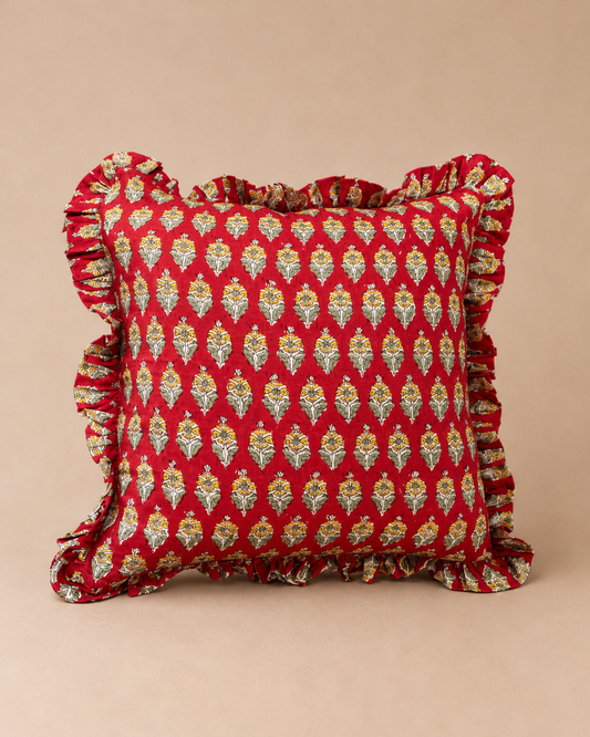 Red square cushion with a repeating cream and yellow floral bud print and ruffled trim, the Sonal Red Square Cushion on a neutral backdrop.