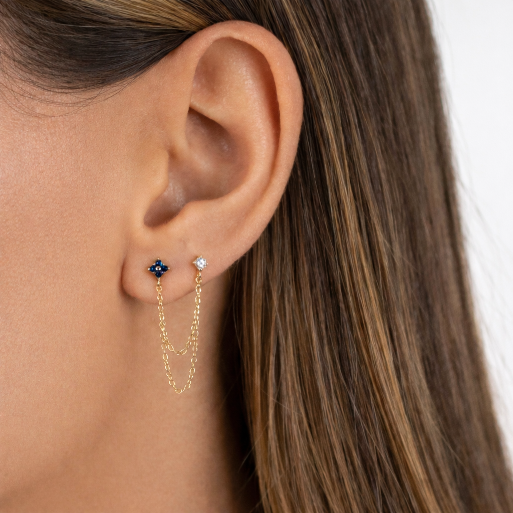 Sonoma Set worn on the ear in gold, a sapphire-blue stud and a clear crystal stud linked by a draped chain.