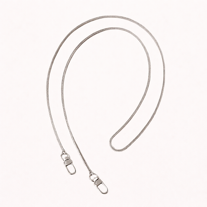 Delicate silver snake-chain phone strap coiled flat, mirroring the gold version with matching lobster clasps.