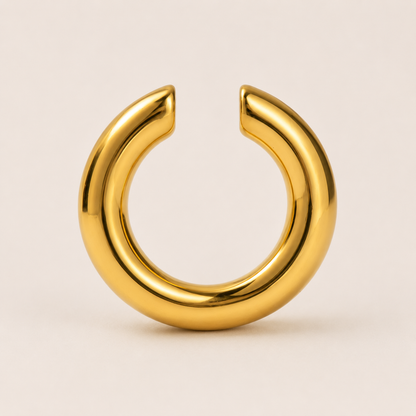 The Sperlonga EAR CUFF in gold, a smooth open-ended tube cuff shown in a studio flat lay on cream.