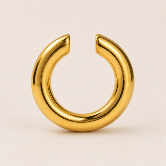 The Sperlonga EAR CUFF in gold, a smooth open-ended tube cuff shown in a studio flat lay on cream.