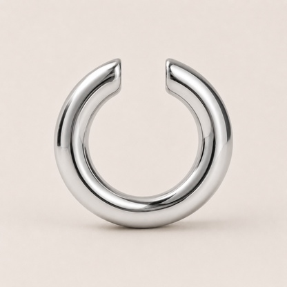 The Sperlonga EAR CUFF in silver, a smooth open-ended tube cuff shown in a studio flat lay on cream.