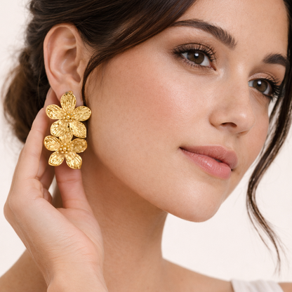 Worn on a model's ear, the Spring Bloom EARRINGS drape two gold flowers gracefully along the earlobe.