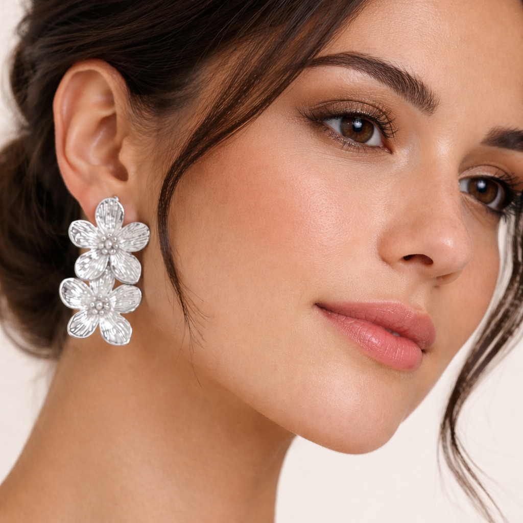 Worn on a model's ear, the silver Spring Bloom EARRINGS cascade with two ridged flower blooms in detail.