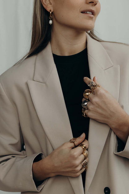 Woman in a beige blazer with both hands stacked in rings, including the silver heart-shaped Street Side RING.