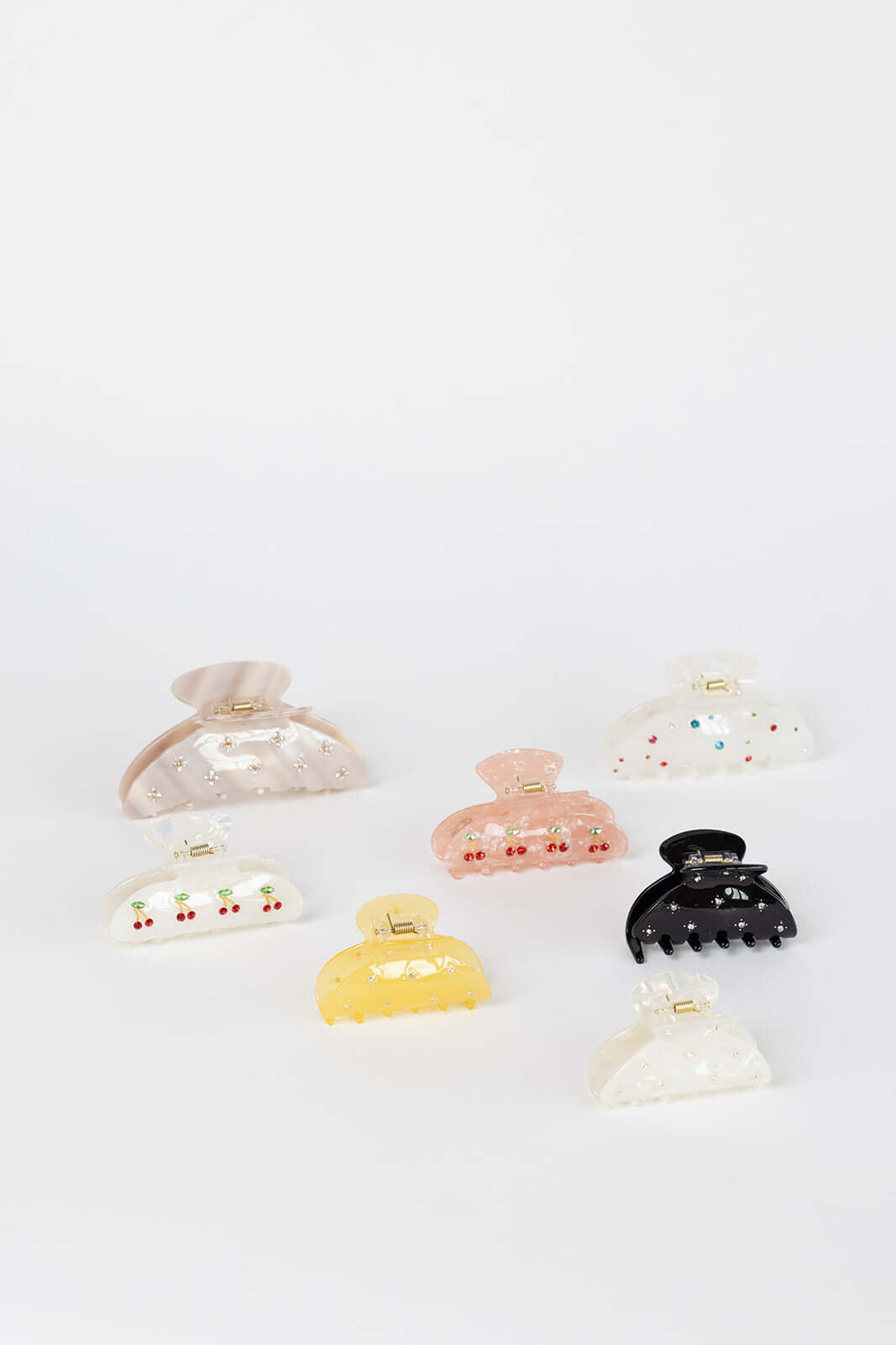 Summer Bliss HAIR CLIP shown among a wide flat-lay assortment of seven differently shaped and colored hair clips, studio shot.